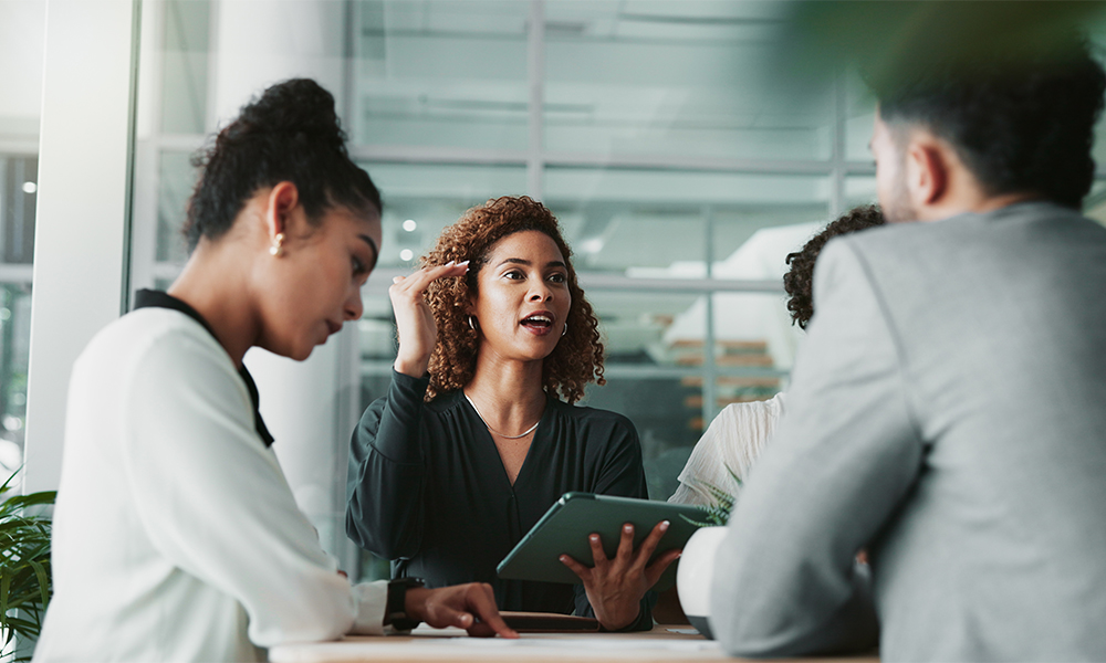 HR-Solutions_Kompetenzfelder Frau mit Tablet bei der Besprechung mit dem Team, Planung und Diskussion